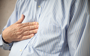 A man touching his chest where he is experiencing heartburn.