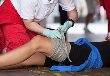 A bystander bandages a leg wound to control bleeding