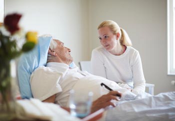man who wants to survive pancreatic cancer in a hospital bed talking to younger relative