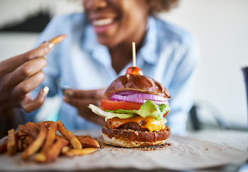 Woman possibly increasing her dietary cholesterol when eating a cheeseburger and fries