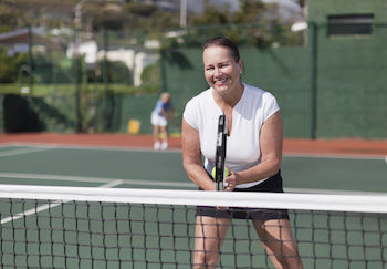 Older woman playing tennis on court