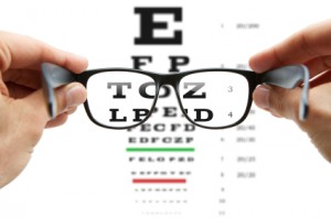 person holding glasses up to vision chart