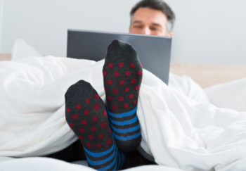 man in bed on laptop