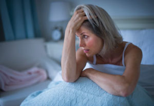 woman sitting up in bed holding head