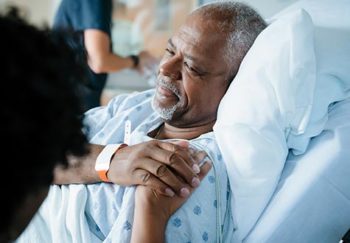 man in hospital bed, holding someone's hand
