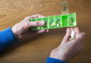 person taking medication out of pill box