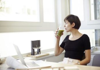A woman taking a break to drink her smoothie to create a healthy workplace environment