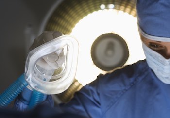 anesthesiologist using a gas mask to sedate a patient before surgery