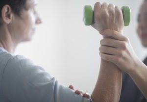 Physiotherapist and patient, training with dumbbell