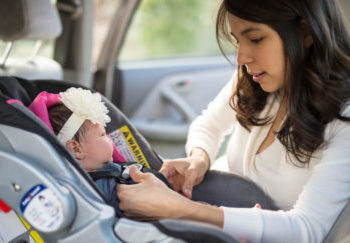 Mom buckling infant into car seat