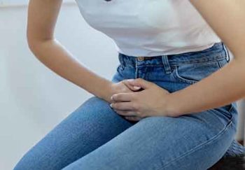 Pelvic discomfort, experienced by this woman in jeans, could be a sign that you need to do pelvic floor exercises, or Kegels.