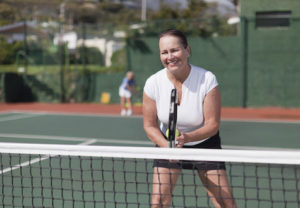 Older woman playing tennis on court instead of walking 10,000 steps