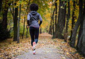 Woman jogging through the woods, how to track your period