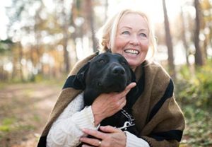 a woman hugging a black lab outdoors