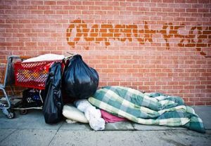 a person sleeps on a sidewalk with trash bags