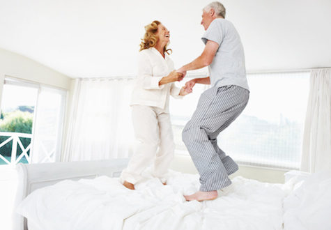 husband and wife jumping on the bed