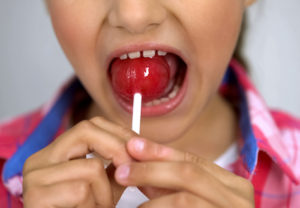 child with a lollipop and what sugar does to your teeth