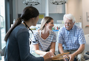older man with younger family member talking to doctor