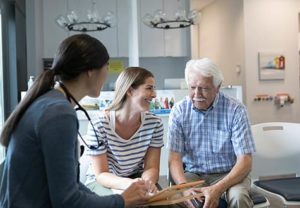 older man with younger family member talking to doctor