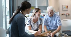 older man with younger family member talking to doctor