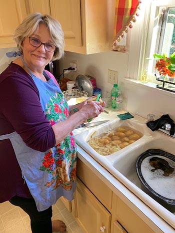 Marcia Oglesby peeling potatoes in a sink