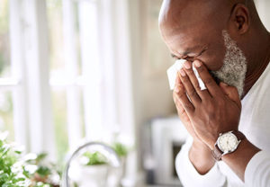 A man with hypertension blows his nose. He's in need of a decongestant that won't raise his blood pressure.