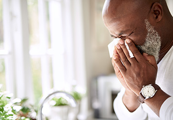 A man with hypertension blows his nose. He's in need of a decongestant that won't raise his blood pressure.