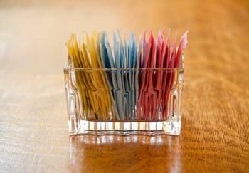 A container with several different packets of sugar substitutes.