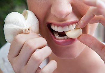 person eating garlic, attempting to prevent coronavirus