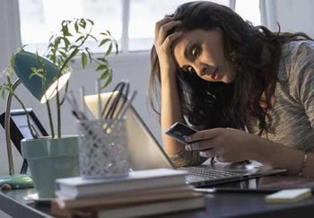 woman checking coronavirus news on her cell phone and laptop