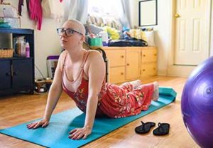 This woman with cancer doing yoga is at higher risk of dying from the coronavirus, but keeping healthy through exercise and treatment.