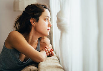 woman looking sadly out a window