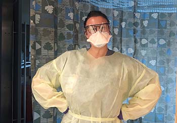 Registered nurse Meredith Farmer standing in front of a hospital room, wearing PPE