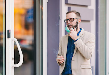 Man removing his face mask to smoke a cigarette during coronavirus pandemic