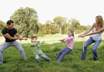 mom and dad keep their kids active with a tug-of-war game outside