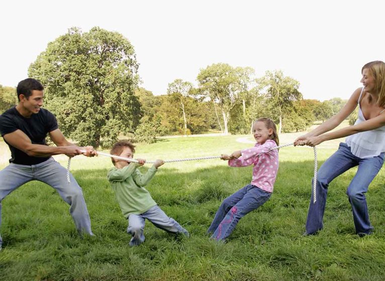 mom and dad keep their kids active with a tug-of-war game outside