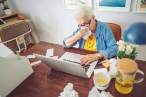 sick older woman having a virtual medical appointment at her table