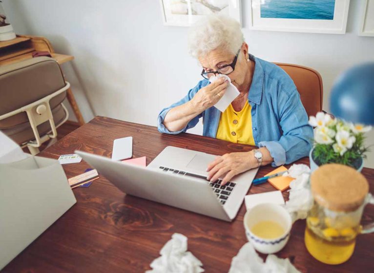 sick older woman having a virtual medical appointment at her table