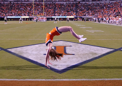 UVA cheerleader doing a back handspring at a football game.