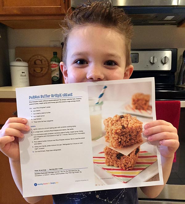 child standing in kitchen, holding the peanut butter krispie treats recipe