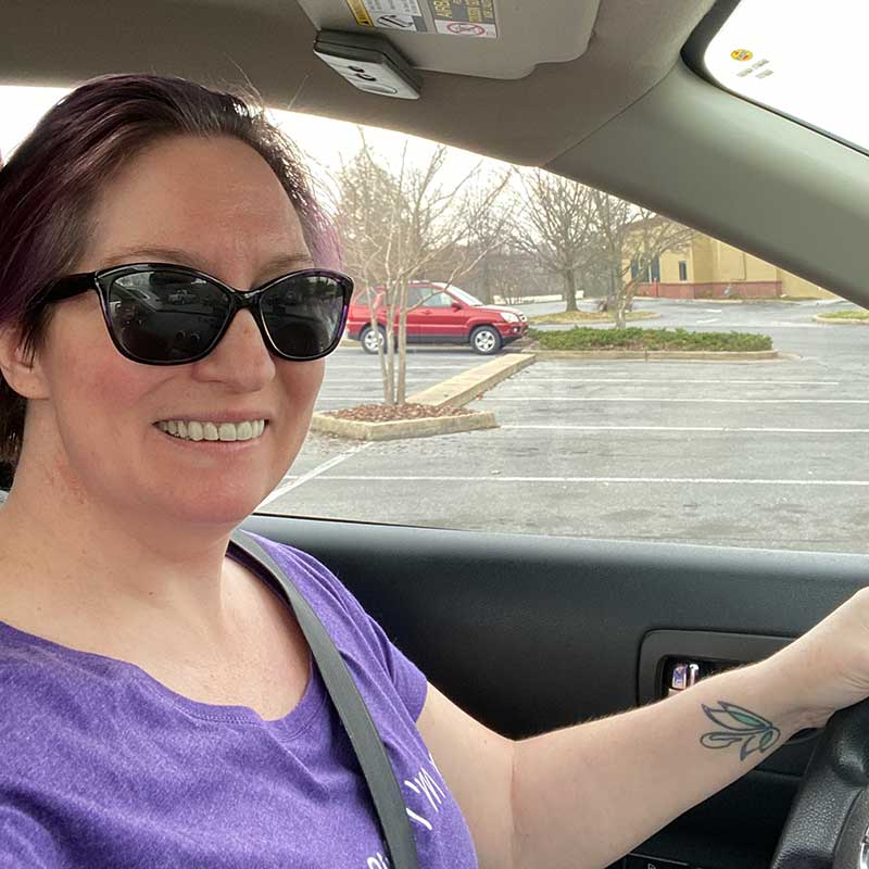 Charity in her car with hand on the steering wheel, driving for the first time since her stroke