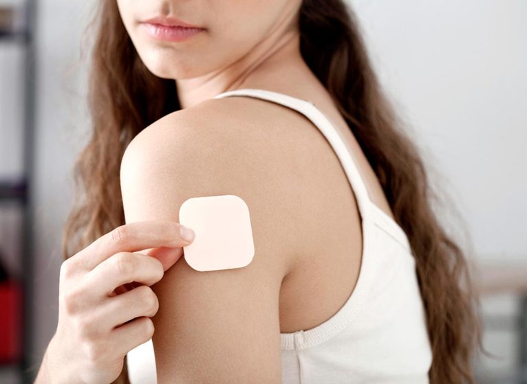 person putting transdermal patch on arm