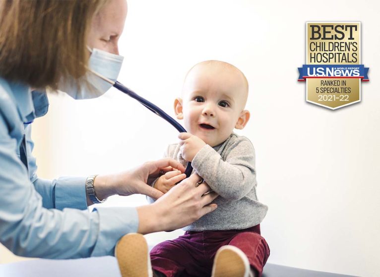 a baby grabbing a doctor's stethoscope during an exam. Badge on image says 'Best Children's Hospitals U.S. News & World Report Ranked in 5 Specialties'