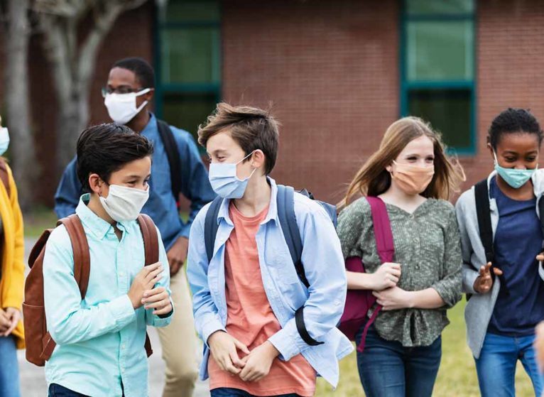 several middle school kids wearing a mask and walking outdoors