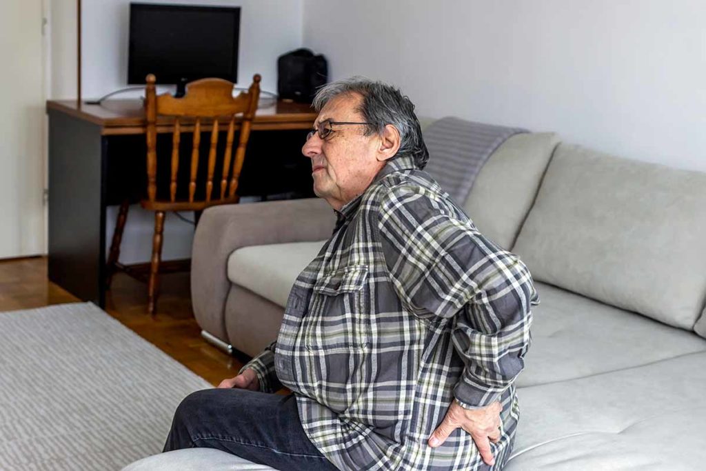person sitting on couch, holding back, flinching