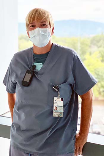 Julie Comer wearing a mask, standing in front of window