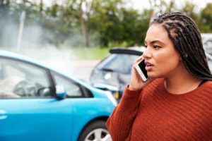 A young woman is on the phone with following a fender bender between two cars