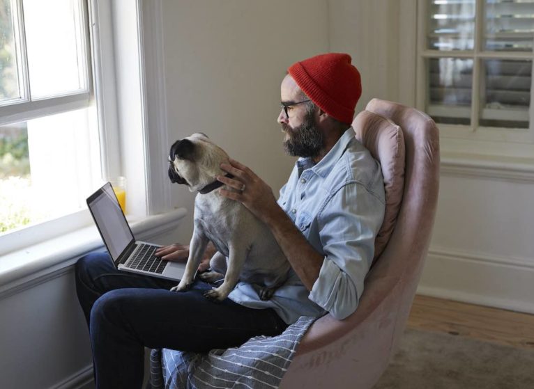 man working from home with dog on lap