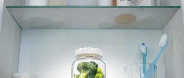 Pieces of broccoli in a pill bottle in a medicine cabinet.