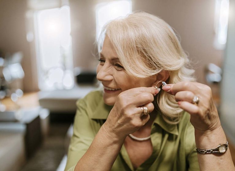 older woman holding a hearing aid